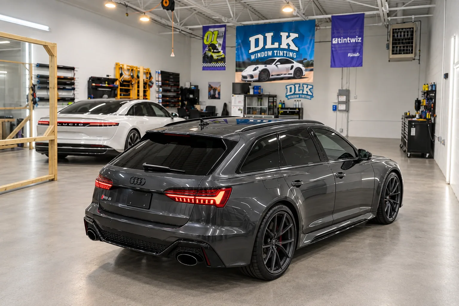 Graphite Audi RS6 with tinted rear glass and a white Lucid in the workshop